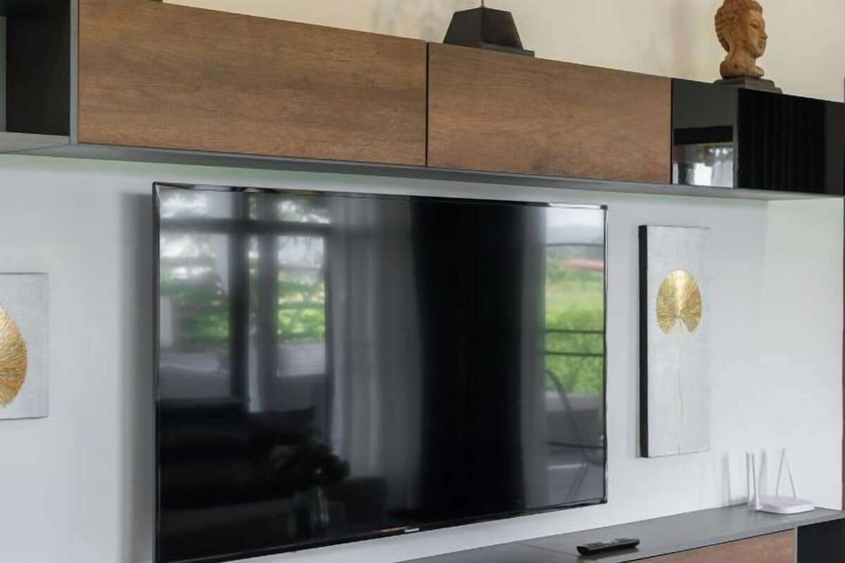 Una cocina moderna con un televisor de pantalla plana grande, armarios de madera y una escultura decorativa en la encimera.