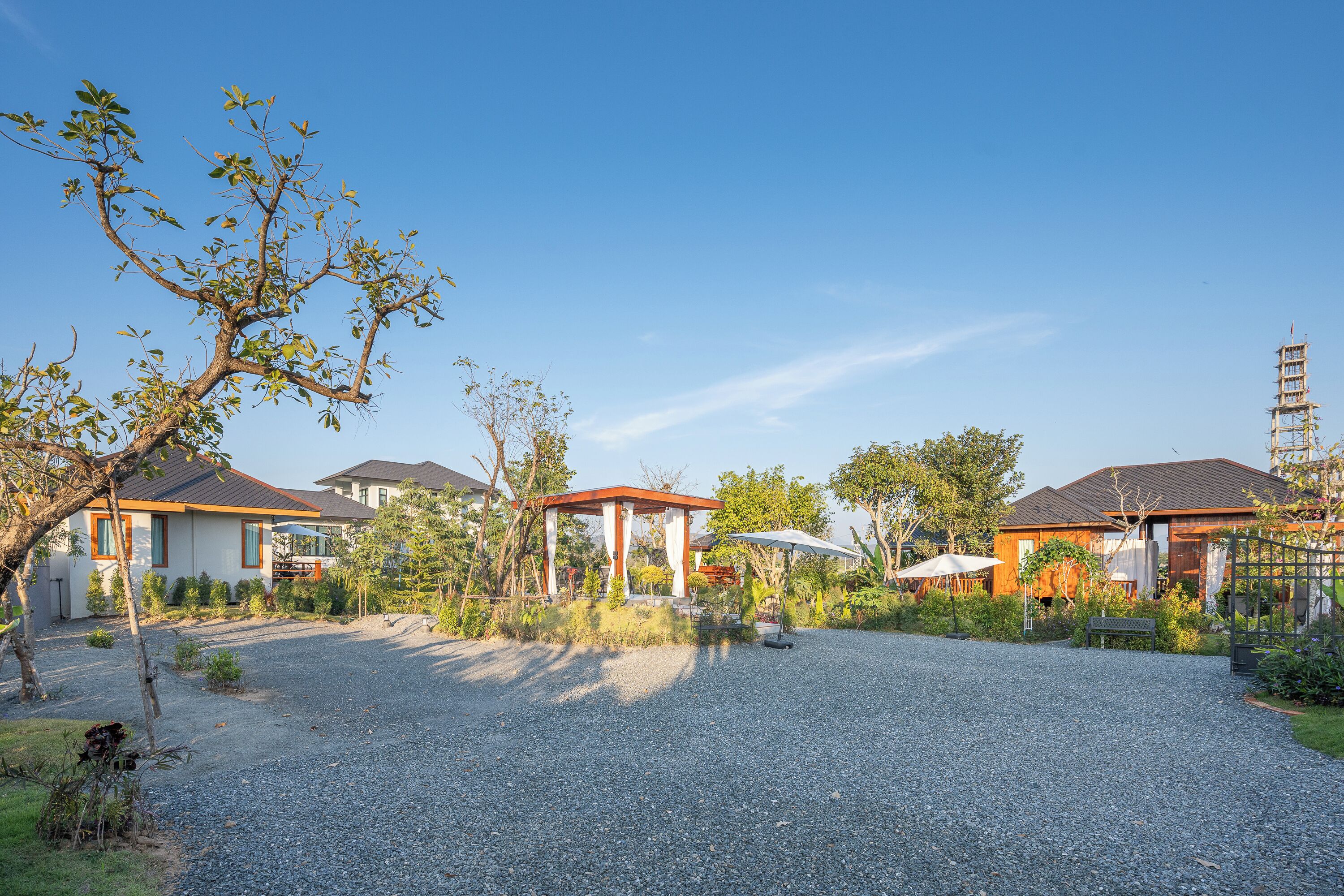A residential area with houses, a gazebo, and a gravel driveway.