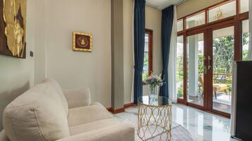 A modern living room with a beige sofa, a glass coffee table, and a large window with blue curtains.