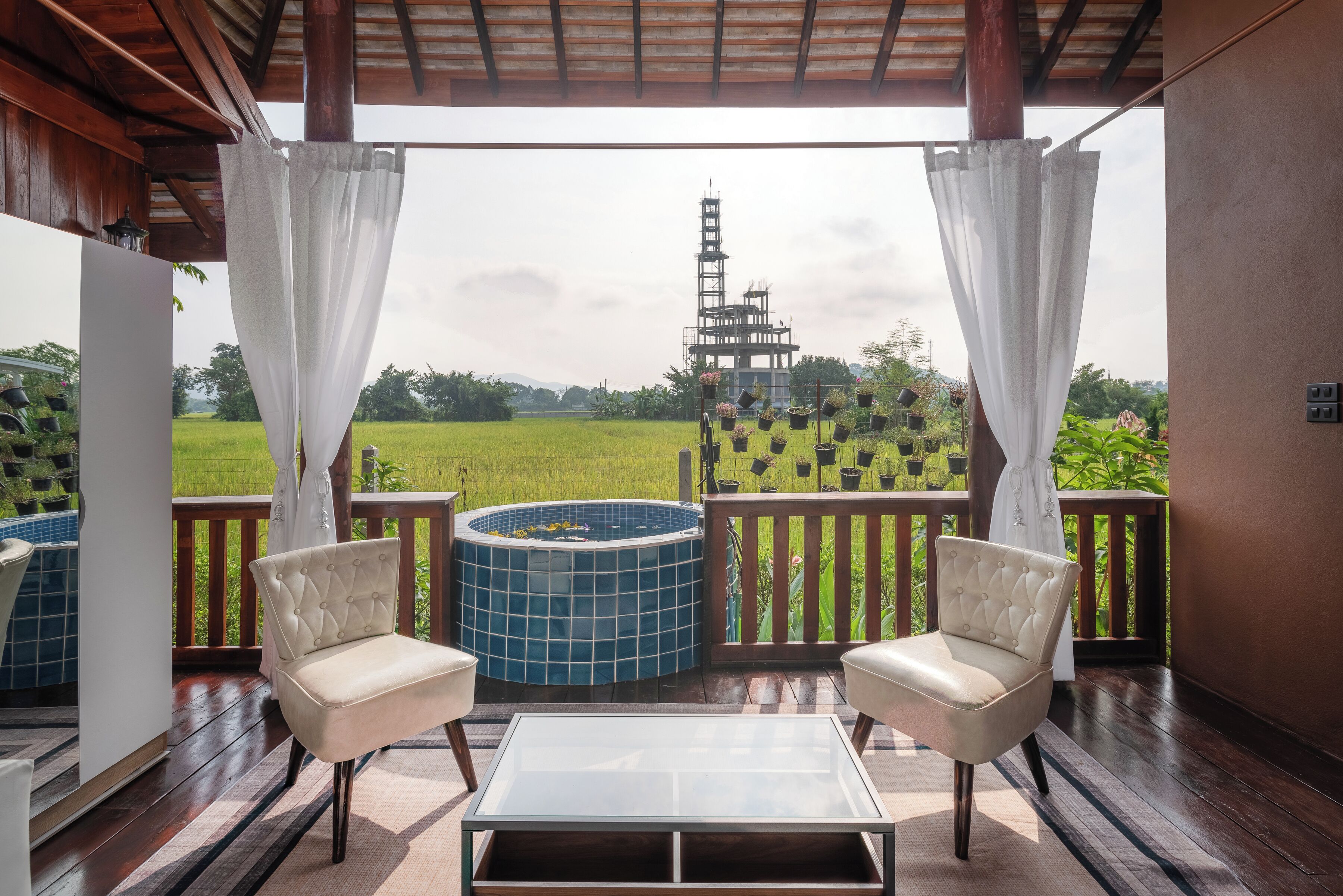 A balcony with two chairs, a glass table, and a hot tub.