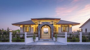 A modern house with a prominent entrance, a well-maintained garden, and a clear view of the sky.