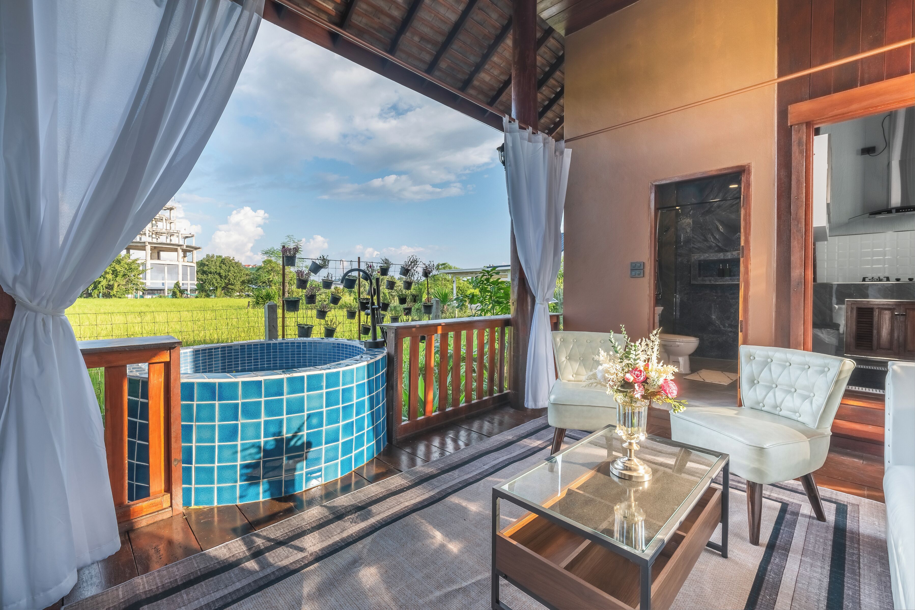 Un balcón con un jacuzzi, un sofá blanco y una mesa de centro de cristal.