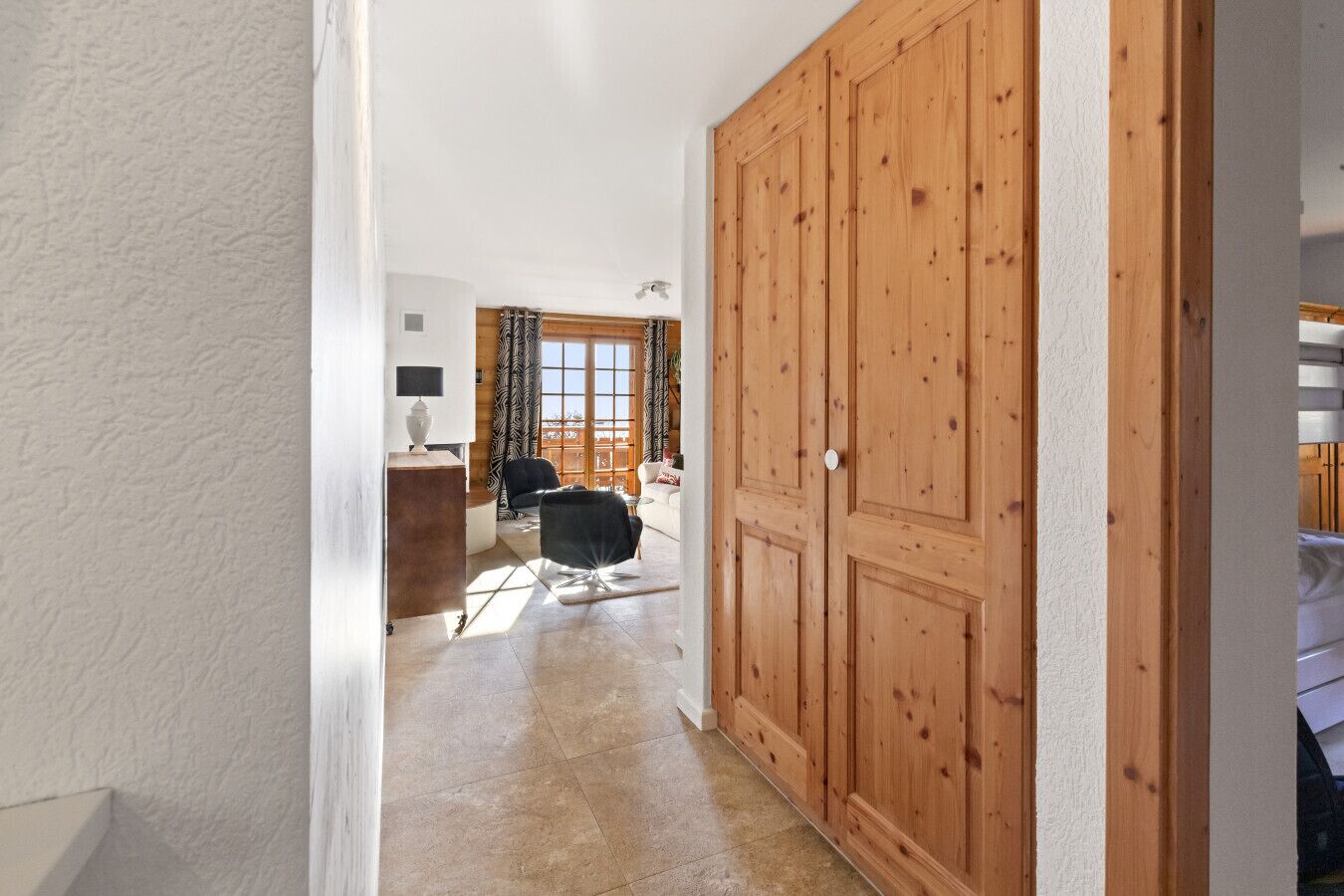 Ein Flur, der zu einem Raum führt, in dem man einen großen Schrank aus Holz, einen Schreibtisch mit einer Lampe und einen Stuhl sieht.