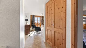Ein Flur, der zu einem Raum führt, in dem man einen großen Schrank aus Holz, einen Schreibtisch mit einer Lampe und einen Stuhl sieht.