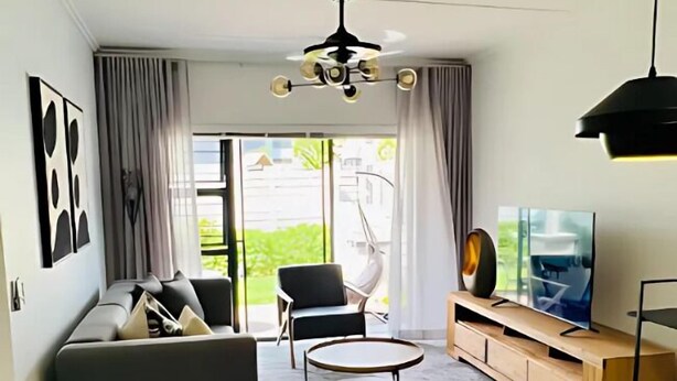 A modern living room with a sofa, a coffee table, a TV, and a ceiling fan. - The Henlee Apartment Tocara (Chartwell)