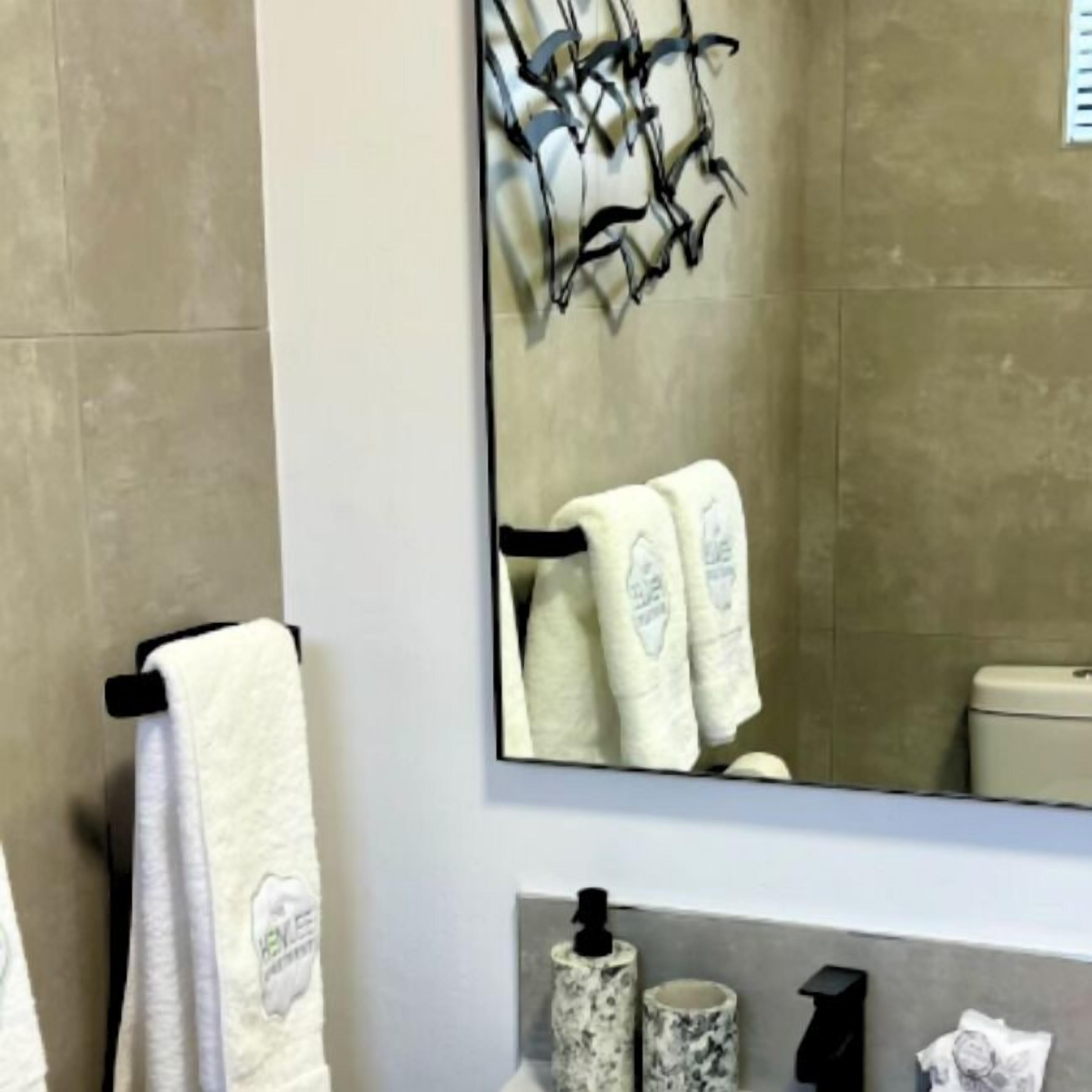 Un baño con un espejo grande, un perchero y un inodoro.