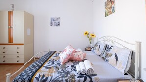 A bedroom with a bed, a wardrobe, a nightstand, and a wall with a painting. -  Villa Aloha In Porto Cesareo Ac (Porto Cesareo)