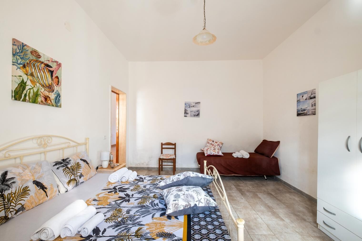A bedroom with a bed, a chair, a sofa, and a wardrobe.