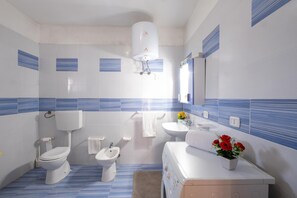 A modern bathroom with a toilet, bidet, sink, and a large mirror. -  Villa Aloha In Porto Cesareo Ac (Porto Cesareo)