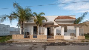 A two-story house with a tiled roof, a gated entrance, and a small porch area. -  Villa Aloha In Porto Cesareo Ac (Porto Cesareo)