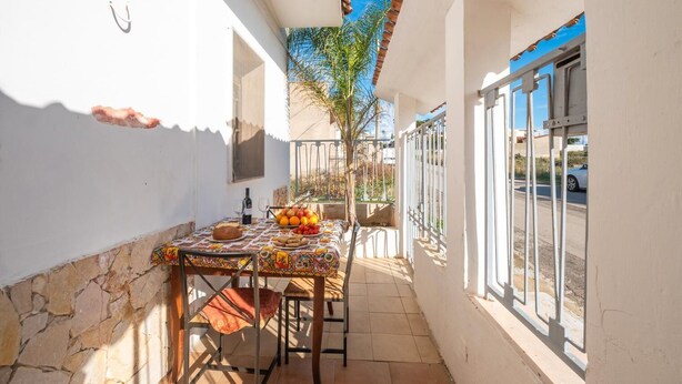 A narrow outdoor patio with a table set for dining, a chair, and a small plant. -  Villa Aloha In Porto Cesareo Ac (Porto Cesareo)