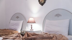 Een slaapkamer met twee bedden, een nachtkastje met lamp en een decoratief object aan de muur.