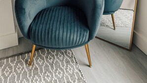 A modern room with a teal armchair, a large mirror, and a bed with a grey headboard. - Stylish newly refurbished 2-bed retreat in the heart of London (London)