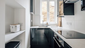 A modern kitchen with a built-in oven, a sink, and a window with a view of a brick wall. - Stylish newly refurbished 2-bed retreat in the heart of London (London)