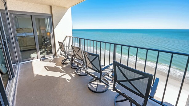 Un balcon avec vue sur l’océan, équipé de chaises et d’une table.