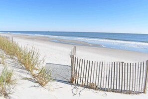 A beach with a wooden fence and sand dunes.