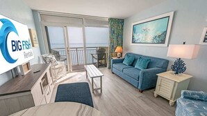 Ein modernes Wohnzimmer mit großem Fenster, einer Couch, einem Couchtisch und einem Fernseher.