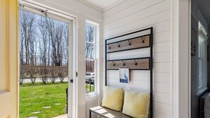 A room with a bench, a wall-mounted coat rack, and a door leading to a yard.