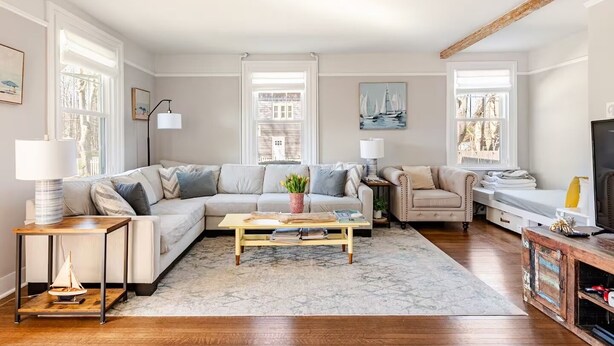 A living room with a sectional sofa, a coffee table, a side table with a lamp, a television, and a bookshelf.