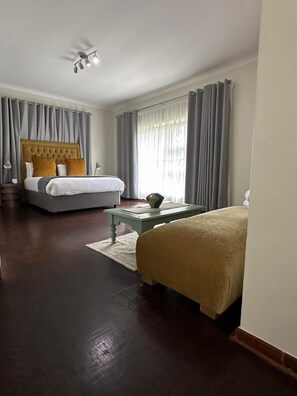 A hotel room with a large bed, a smaller bed, a desk, and a ceiling fan.