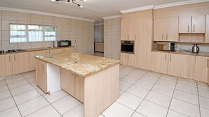 Un'ampia cucina con mobili chiari in legno, un'isola con piano di lavoro in granito e un'ampia finestra che offre luce naturale.