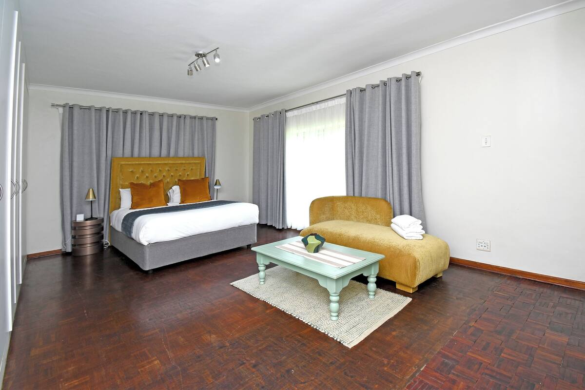 A hotel room with a bed, a sofa, a coffee table, and a window with curtains.
