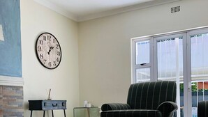 Un soggiorno moderno con un tavolino in vetro, una poltrona a righe, un orologio a parete e un camino.
