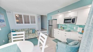 A compact kitchen with white cabinets, a stainless steel refrigerator, and a microwave. - New Remodeled, Corner Oceanfront Beach Cove, Pools (North Myrtle Beach)