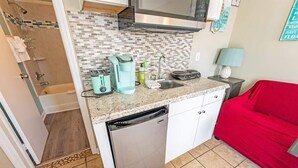 A compact kitchen with a dishwasher, a coffee maker, and a sink.