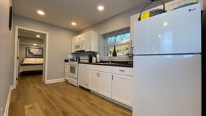 A modern kitchen with white cabinets, a built-in oven, a microwave, and a refrigerator.