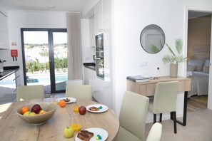 Uma zona de refeições moderna com mesa de madeira, cadeiras e vista para a piscina.
