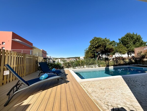 Zona junto a la piscina con sillones de descanso y una piscina.