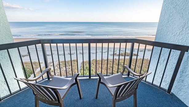 A balcony with two chairs facing a beach view. - Direct Oceanfront, Newly Remodeled & Heated Pools! (Myrtle Beach)