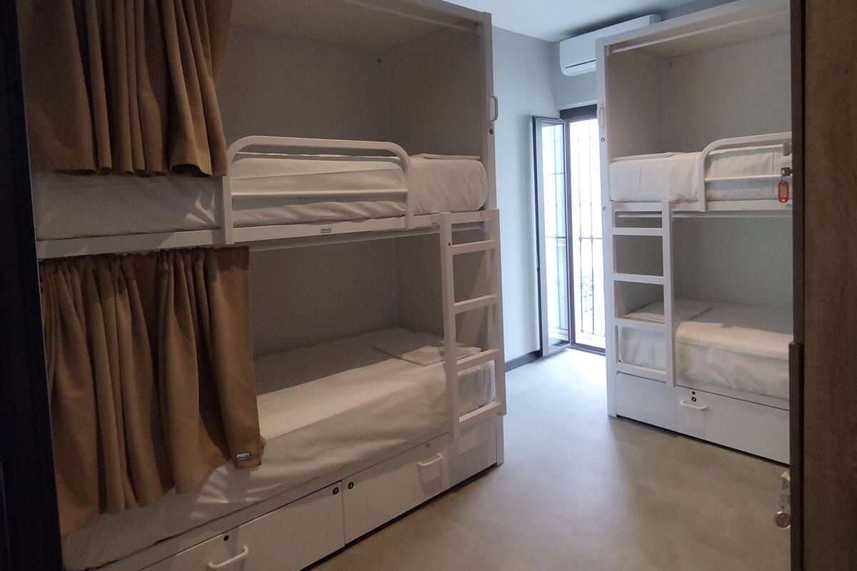 Una habitación con literas, una puerta corredera y una lámpara en el techo.