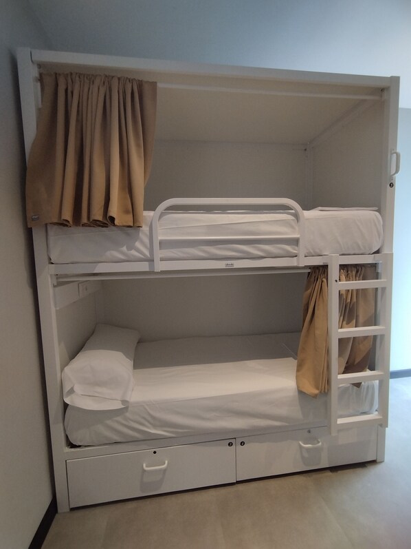 Een stapelbed met een opbergla en een gordijn.