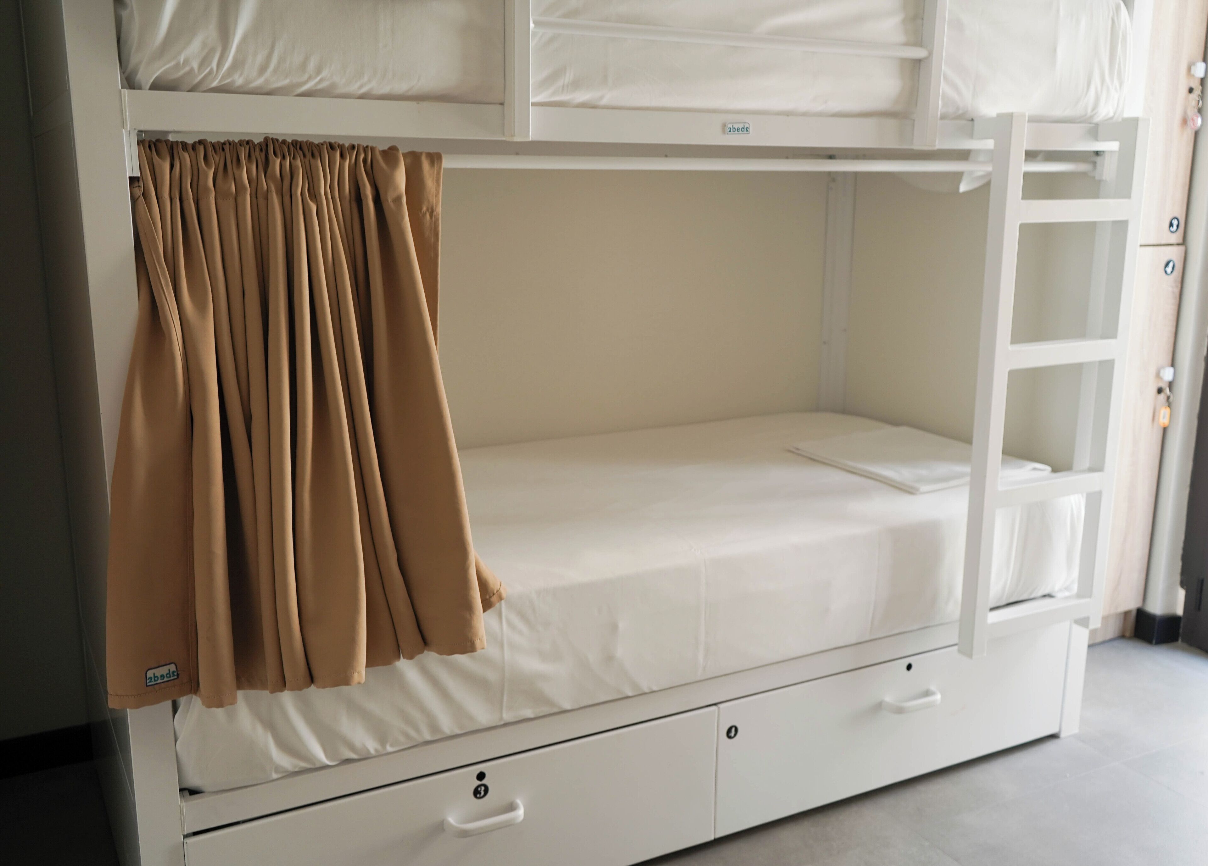 A bunk bed with a curtain, a drawer, and a small shelf.