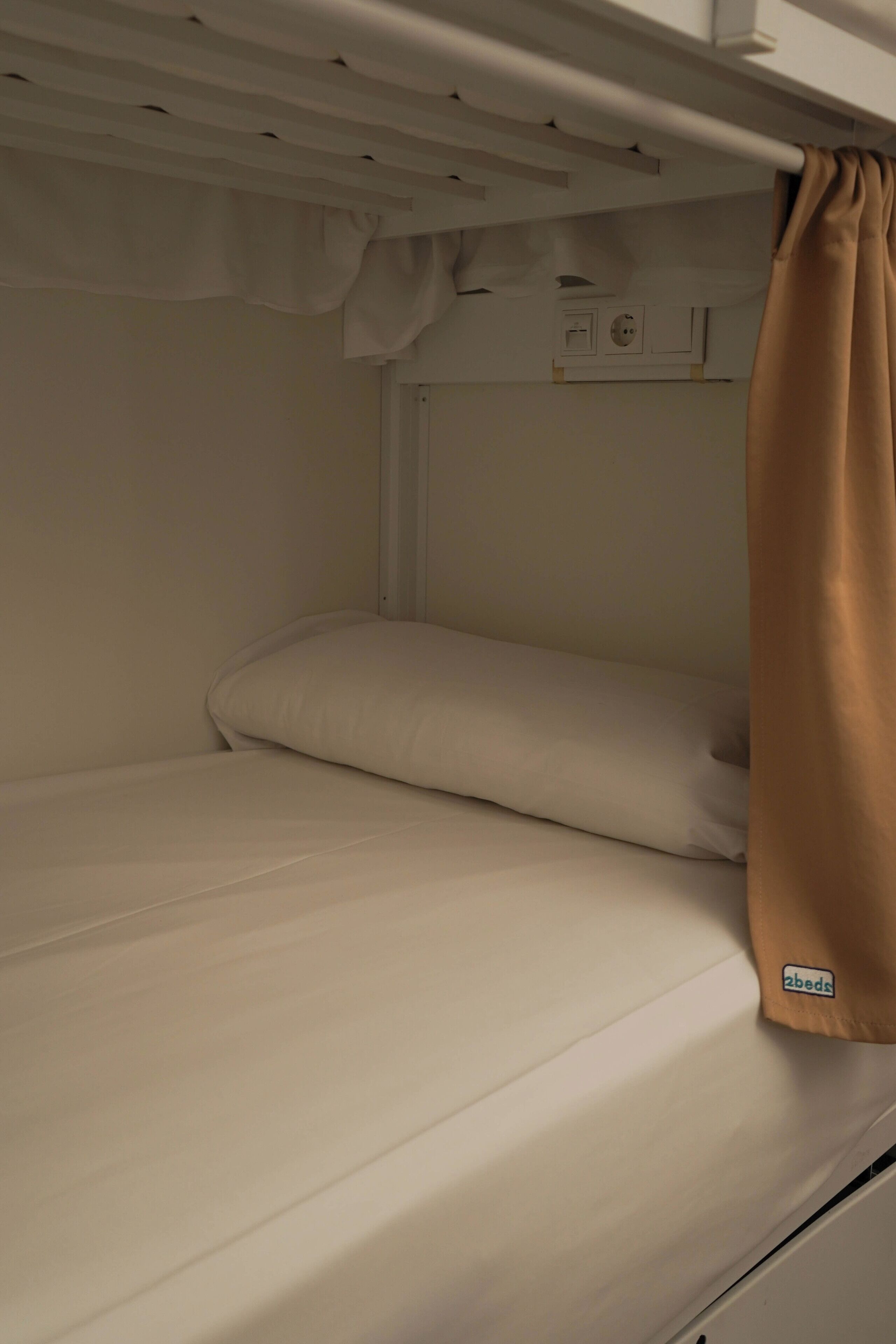 Una cama literera con un almohadón y una manta.