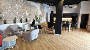 A modern office space with a brick wall, wooden flooring, and contemporary furniture. - Sweet Sevilla Hostel  (Seville)