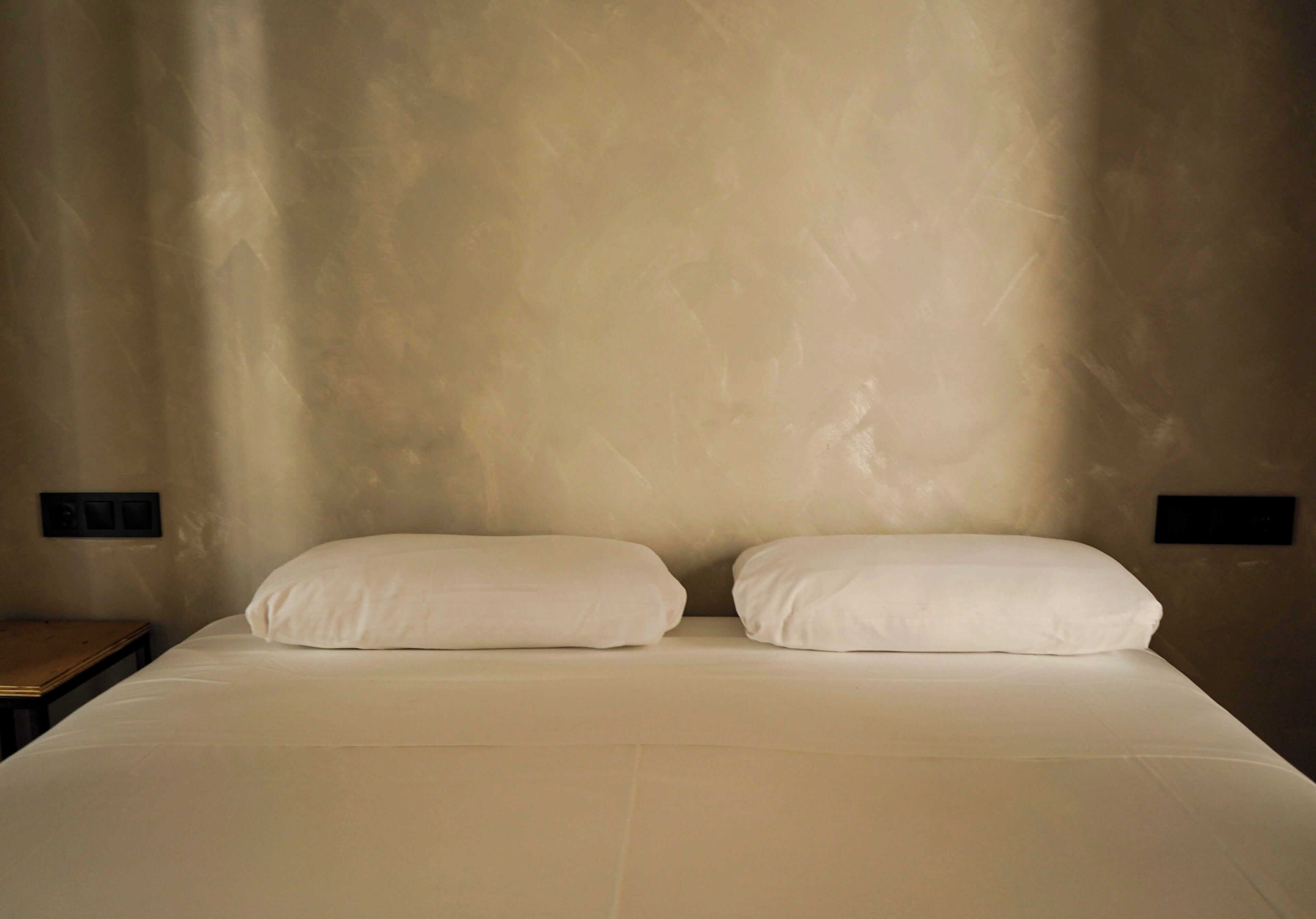 Una cama con dos almohadas y una mesita de noche de madera.