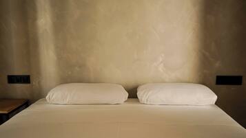 Una cama con dos almohadas y una mesita de noche de madera.