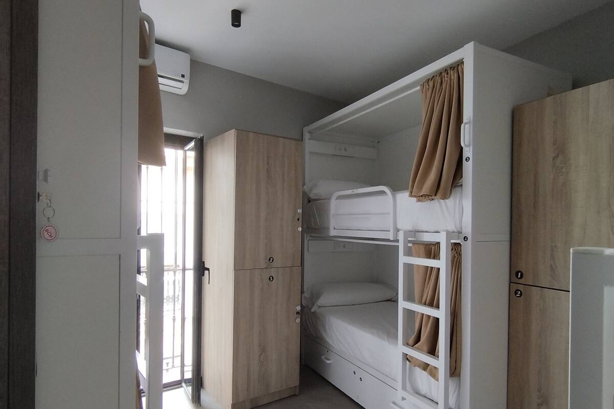 Habitación pequeña con una cama litera, un armario y una puerta que da a un espacio exterior.