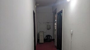 Un couloir étroit, doté d’une moquette rouge, de murs blancs et d’une porte noire au fond.