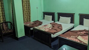Une chambre avec deux lits, une chaise, un climatiseur et un ventilateur de plafond.