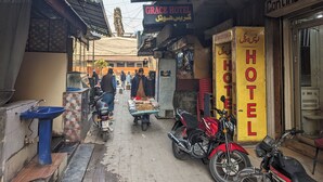 Une rue étroite bordée de boutiques, avec une enseigne d’hôtel bien visible.