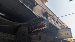 Une enseigne d’hôtel indiquant « GRACE HOTEL » et « Continental Tailors », ce qui signale la présence de ces commerces à proximité.