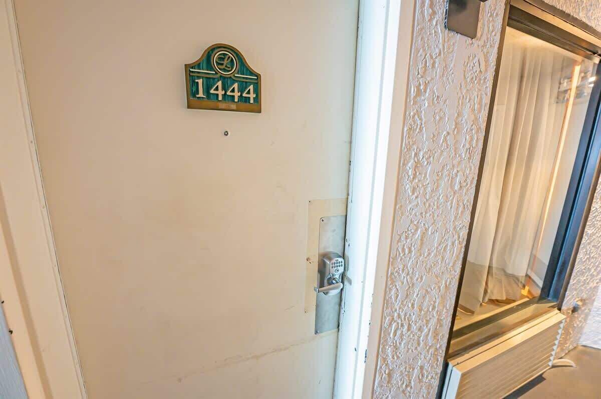 Une porte avec une plaque indiquant le numéro de la maison, un clavier pour ouvrir la porte et un mur à texture.