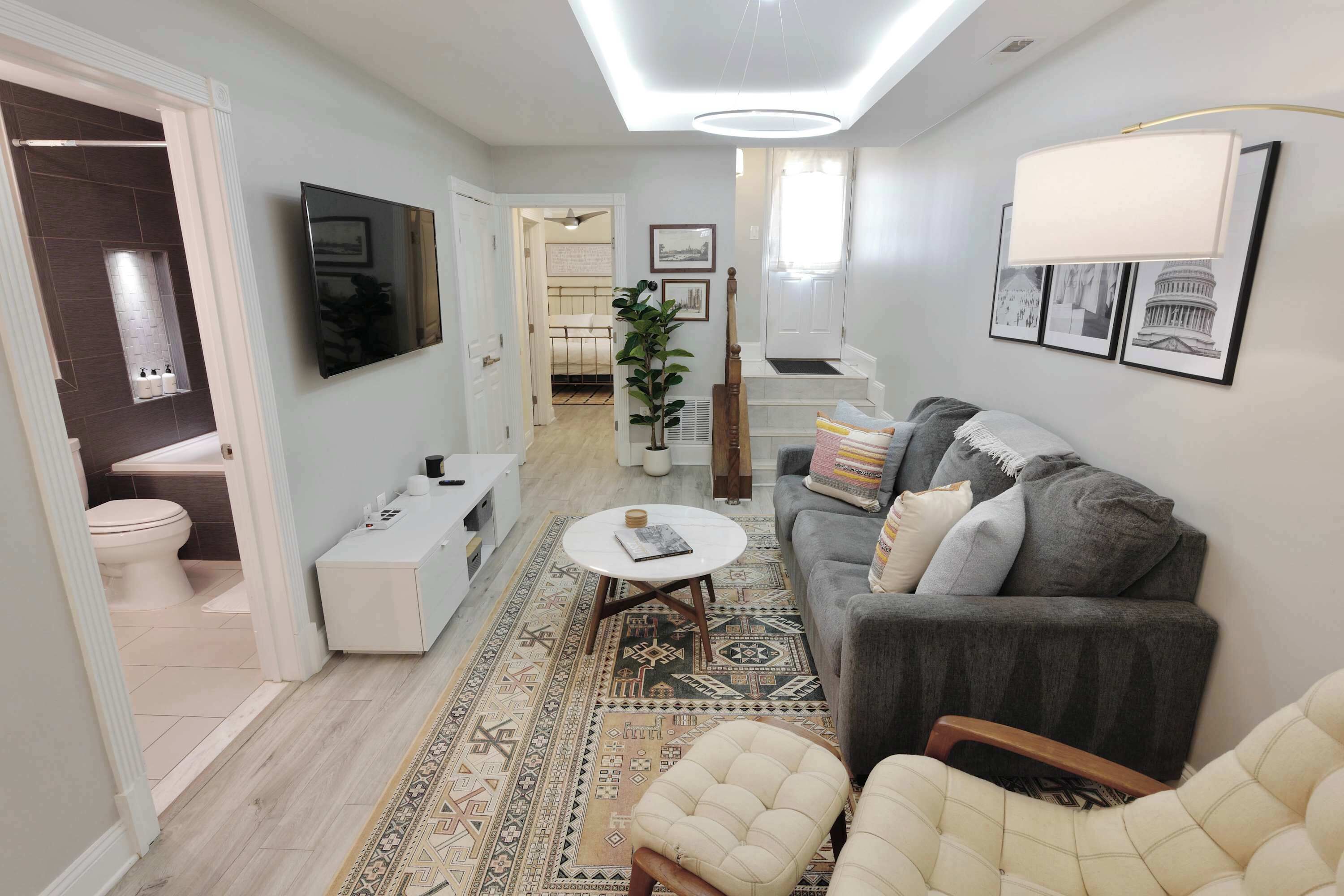 A modern living room with a grey sofa, a white coffee table, and a patterned rug.