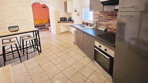 Una cocina moderna con una isla central, electrodomésticos de acero inoxidable y suelo de baldosas.