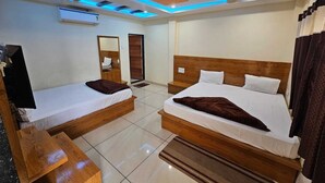 Camera d'albergo con due letti, una testiera in legno, una TV a schermo piatto e un soffitto illuminato di blu.