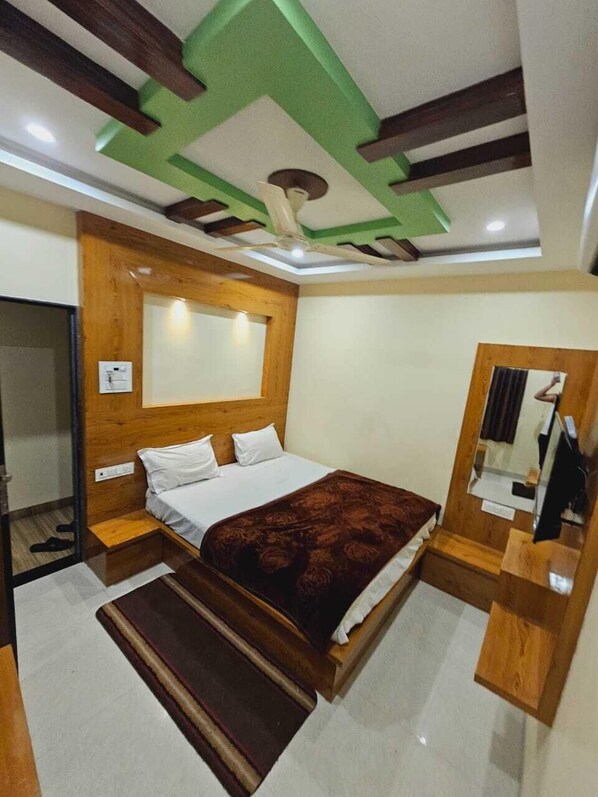 A bedroom with a bed, wooden headboard, a mirror, and a ceiling fan.